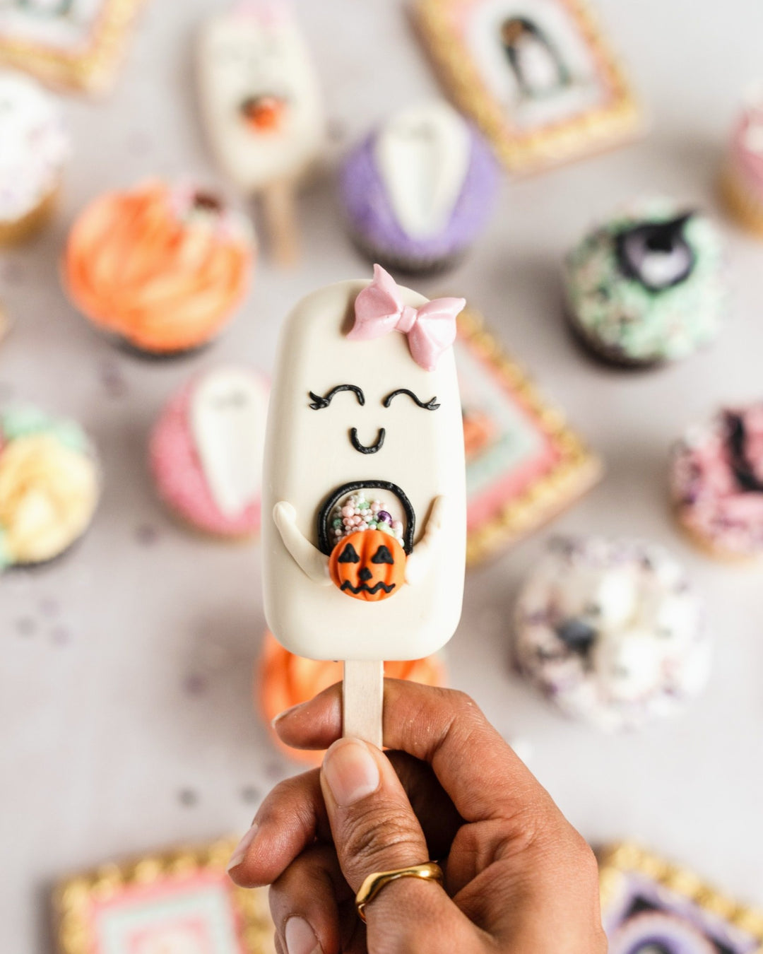 Ghost cakesicle with pink bow held in hand