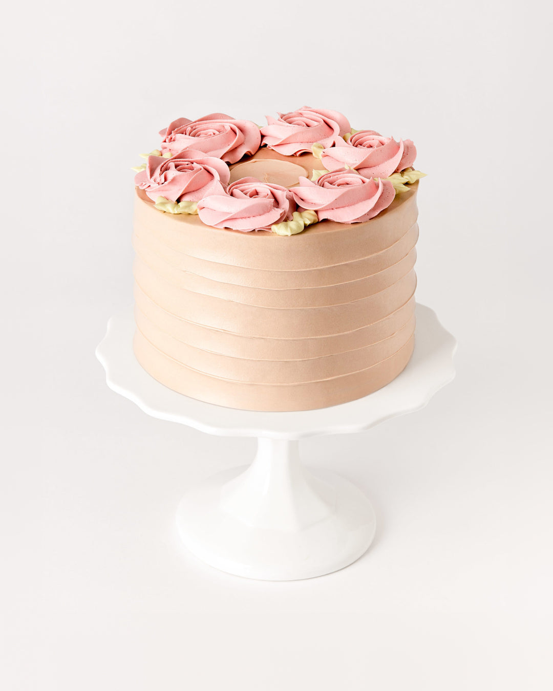 Raspberry chocolate cake with pink buttercream rosettes on a white cake stand