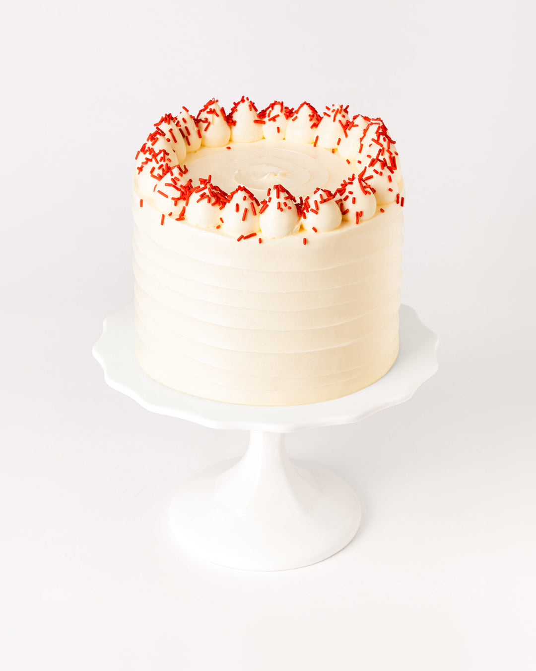 Red velvet cake with cream cheese buttercream and red sprinkles, by Bobbette & Belle