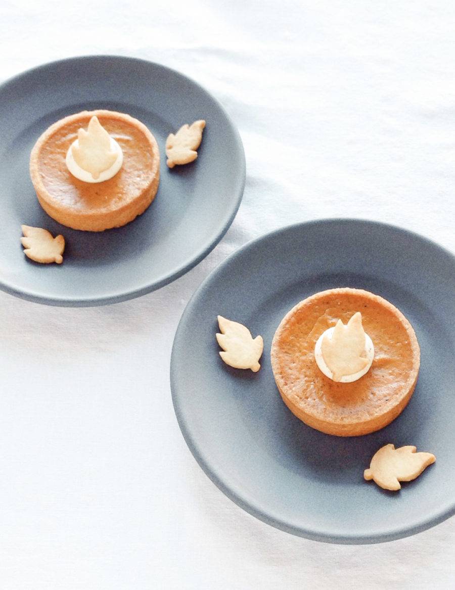 Individual-sized pumpkin pie with buttery crust, spiced pumpkin filling, whipped cream, and a shortbread cookie leaf, perfect for Thanksgiving and fall treats