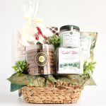 A woven holiday gift basket filled with gourmet treats, including ginger cookies, caramel corn, English toffee, shortbread, hot chocolate, marshmallows, and a decorative polar bear sugar cookie.