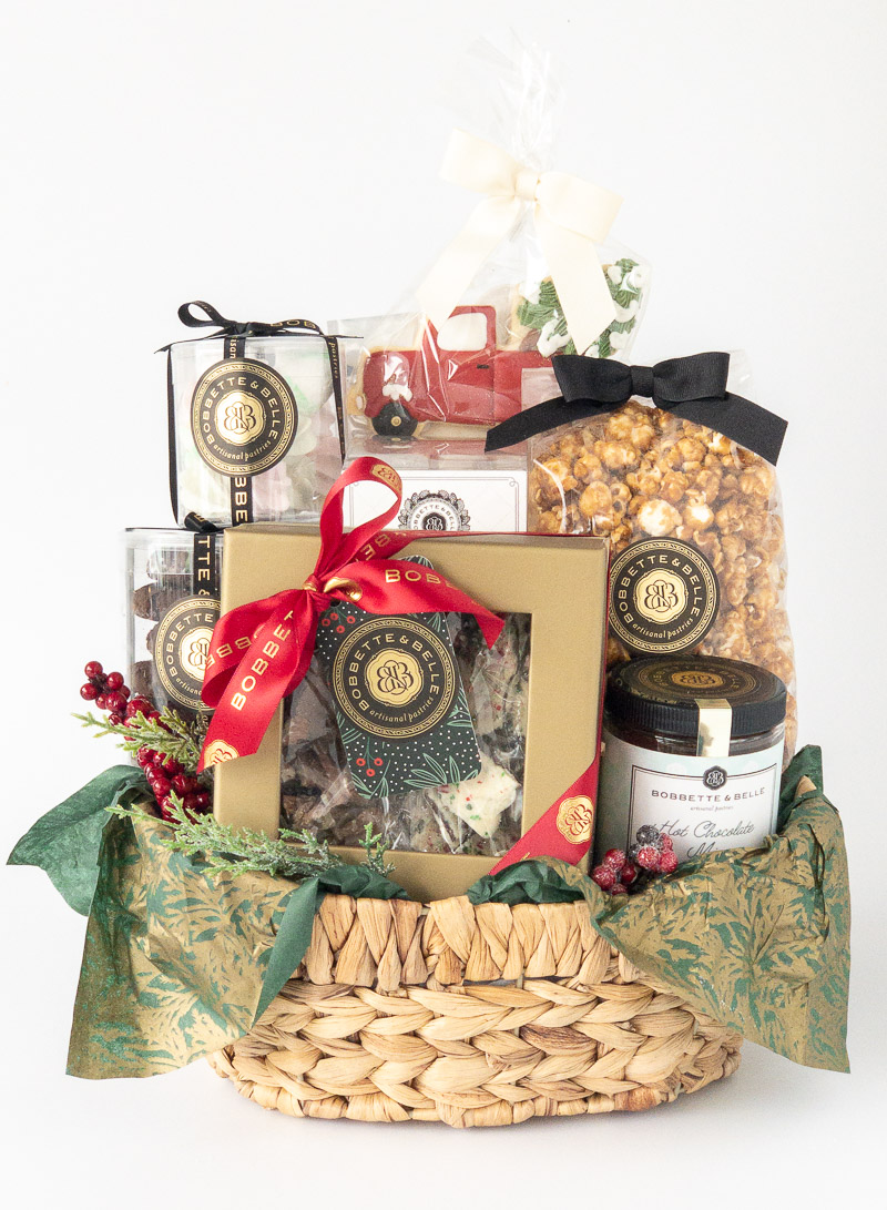 A beautifully arranged holiday gift basket featuring gourmet treats, including caramel popcorn, chocolates, cookies, and preserves, wrapped with festive ribbons and accents.