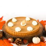 Homemade Thanksgiving pumpkin pie with a buttery crust, smooth spiced pumpkin filling, topped with whipped cream and shortbread cookie leaves