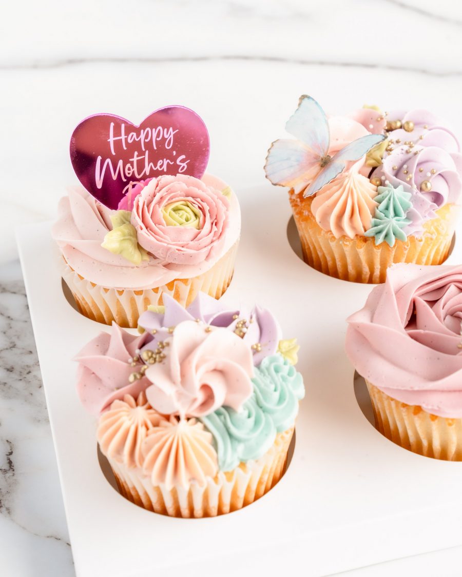 Vanilla Rose swirl cupcakes with Happy Mother's Day heart shaped plaque, sugar butterfly and decorative buttercream piping in shades of soft pink, blue lavender and turquoise