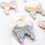 An overhead shot of a selection of gorgeous rainbow pastel butterfly sugar cookies with outline piping in gold.