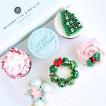 A 6-pack of holiday cupcakes with Christmas tree, wreath, and snowflake designs, topped with tinted vanilla buttercream