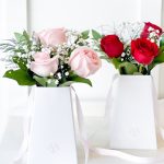 A luxury rose bouquet in a sleek white gift bag, featuring soft pink and deep red roses, accented with baby’s breath and fresh greenery.