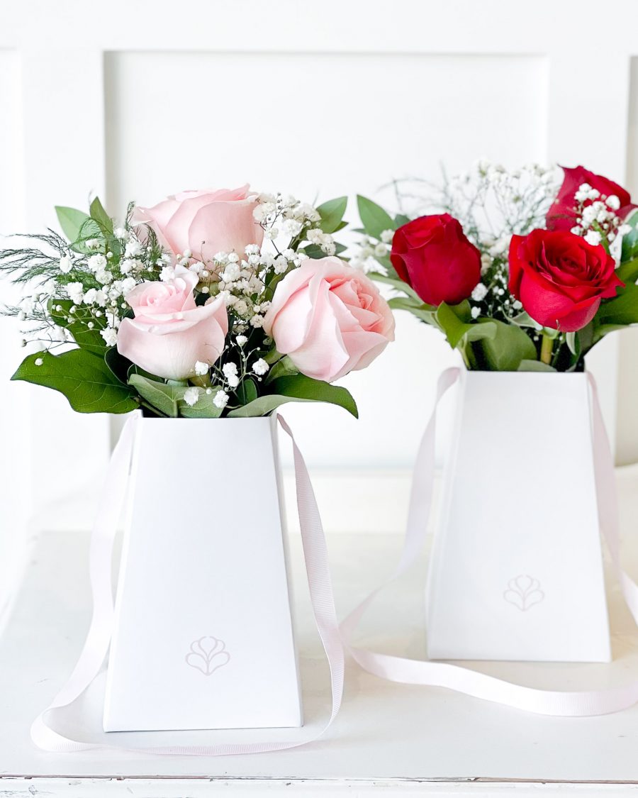 A luxury rose bouquet in a sleek white gift bag, featuring soft pink and deep red roses, accented with baby’s breath and fresh greenery.