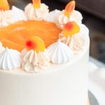Detailed view of the Peaches and Cream Cake showing peach purée, buttercream swirls, meringues, and fuzzy peach candy.