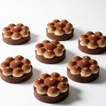 Tiramisu tarts topped with espresso mascarpone cream, set in chocolate shortcrust shells with ganache, cocoa powder, and gold accents.