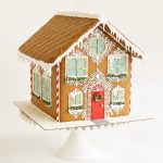 Elaborately decorated gingerbread house with red door, candy canes, and white royal icing