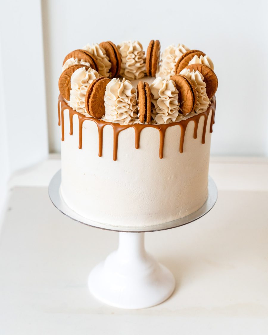 Biscoff cake Front view of a Biscoff cake with vanilla frosting, caramel drip, and cookie garnish
