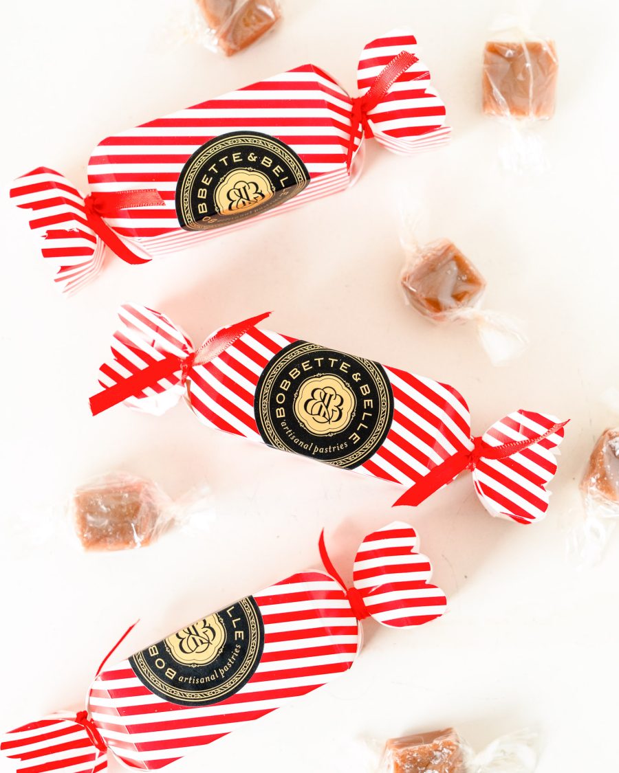 Salted Caramel Stocking Stuffer 4 Three festive red-and-white striped Bobbette & Belle holiday caramel crackers surrounded by individually wrapped caramels.