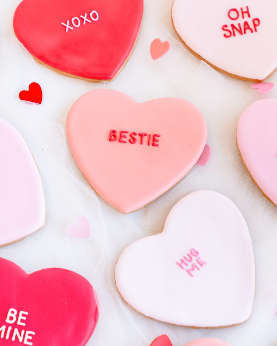 Heart-shaped sugar cookies with fondant icing and Valentine’s messages like XOXO, YAAS, and BE MINE.