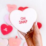 Detailed close-up of fondant heart cookies with Valentine’s sayings in pink and red.