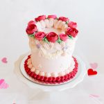 A mini Valentine's cake decorated with red and pink buttercream roses and piped details.