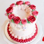 Close-up view of red and pink buttercream roses on a mini Valentine’s cake.