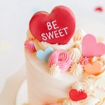 Close-up of pastel candy hearts and piped frosting on a Valentine's mini cake.