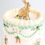 close up of Easter cake with buttercream floral piping carrot details and gold chocolate bunny topper