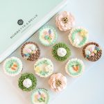Easter cupcakes decorated with pastel buttercream flowers, nests, and bunny designs