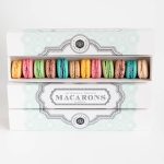 Box of 12 assorted French macarons in pastel colours in elegant packaging on a clean background