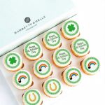 Box of St. Patrick’s Day cupcakes with shamrock, rainbow, and horseshoe edible image toppers