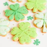 Decorated shamrock sugar cookies with green royal icing and gold sprinkles for St. Patrick’s Day